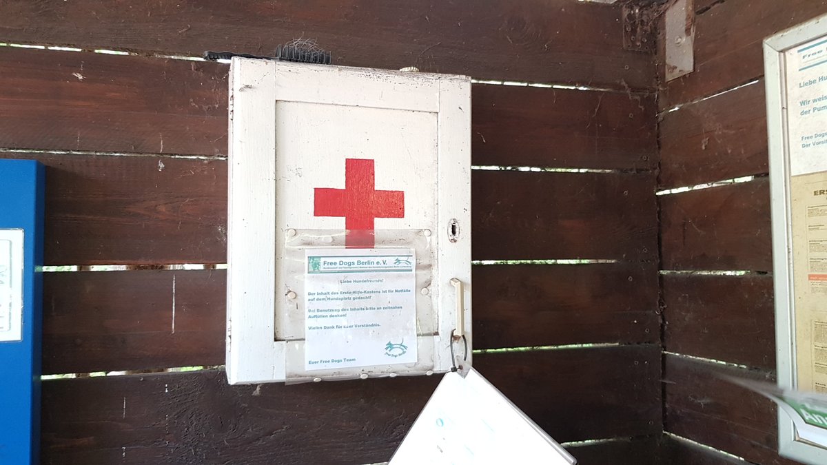 Caja de primeros auxilios para perros con una cruz roja pintada, colgada en la pared